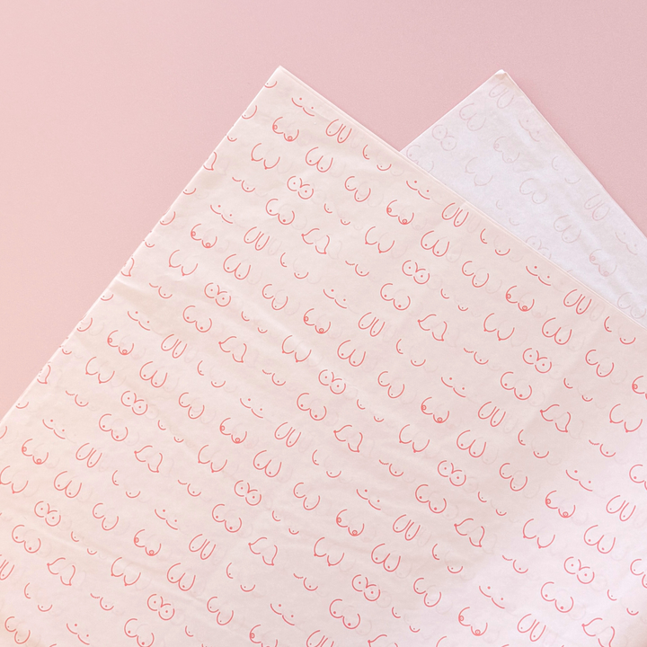 [main] Light Pink tissue paper featuring hot pink shapes of different boobs across the tissue paper to represent breastfeeding. 